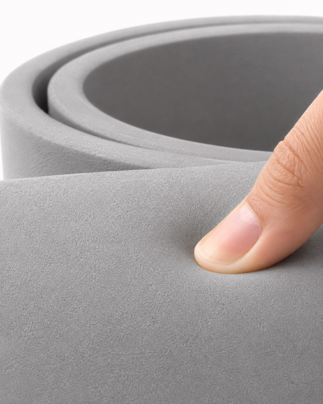 A thumb pressing into the grey cushioning foam, showing the surface giving under gentle pressure.