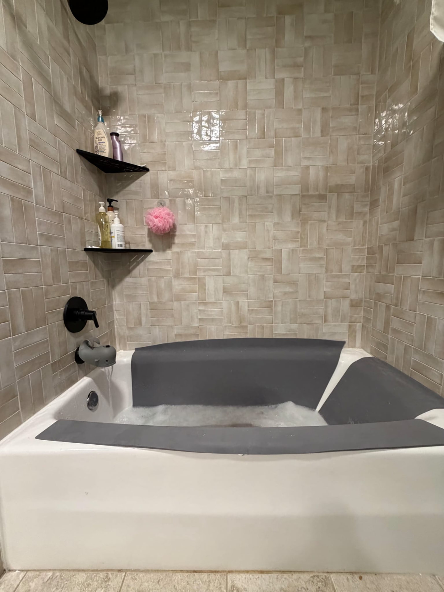 A tiled bathtub with grey foam panels fitted along the back wall, both sides, and front tub edge.